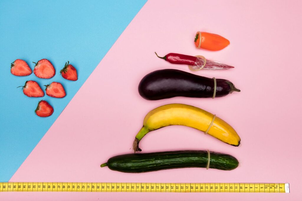 A playful still life featuring fruits and vegetables with condoms on pastel backgrounds, suggesting safe nutrition.